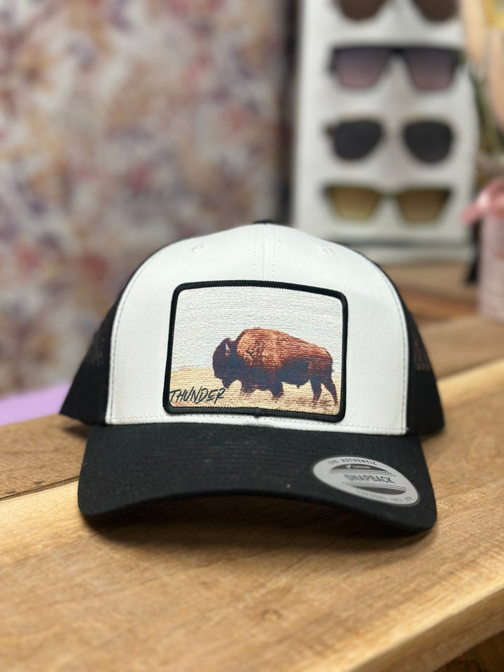 A black and white trucker hat with a graphic of a bison on the front.
