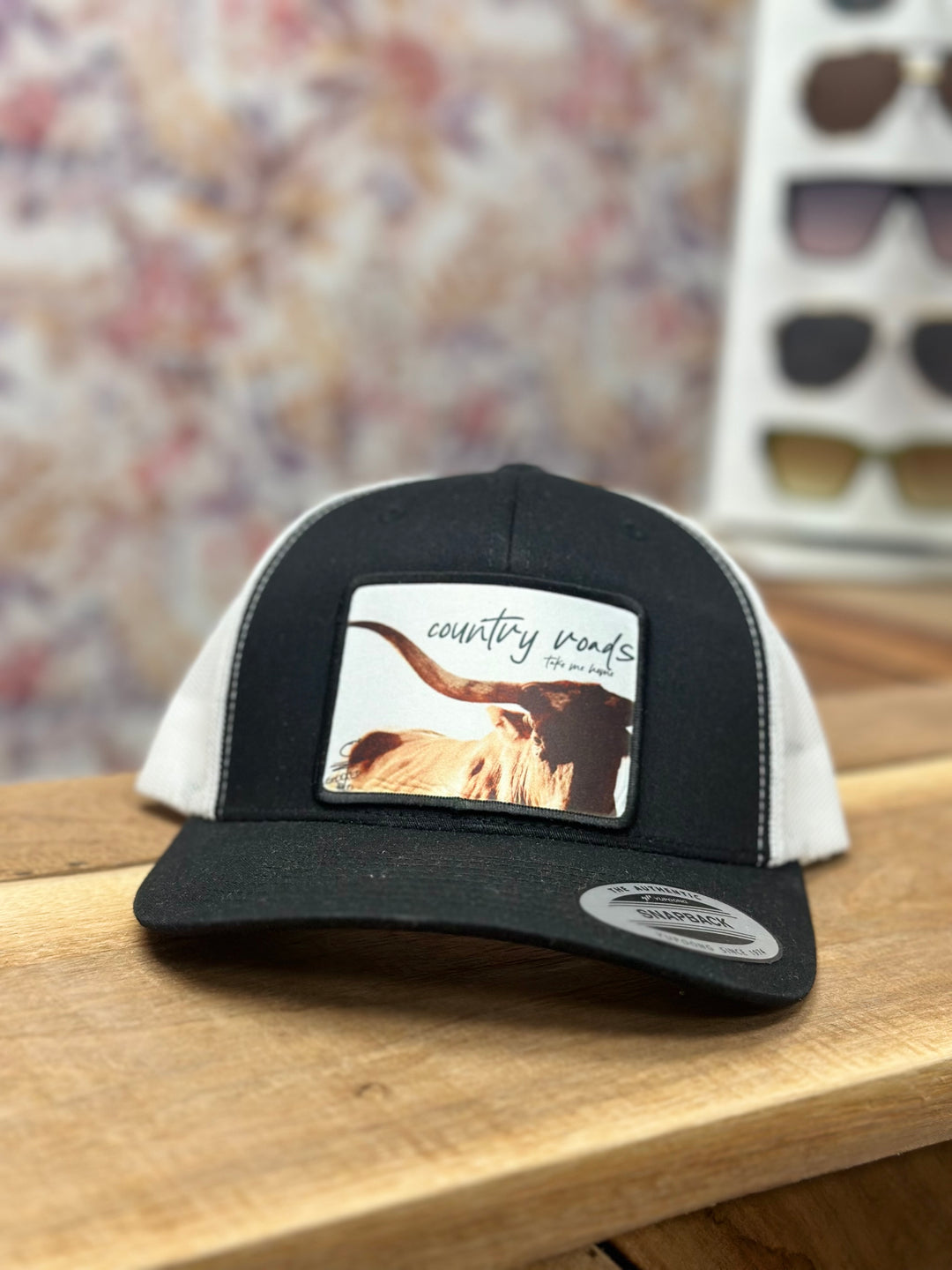 Black and white trucker hat with “country roads take me home” on the front