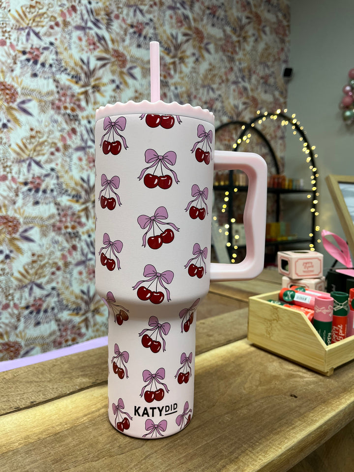 Light pink stainless steel tumbler with screw on lid and easy to hold handle. Design is cherries with pink bows.