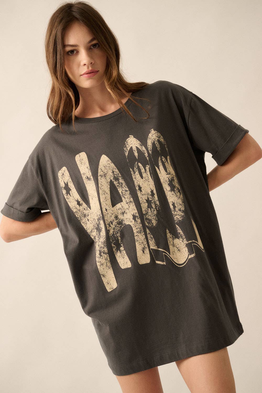 Woman wearing a dark gray t-shirt with 'YALL' printed in large, distressed letters on a plain background.