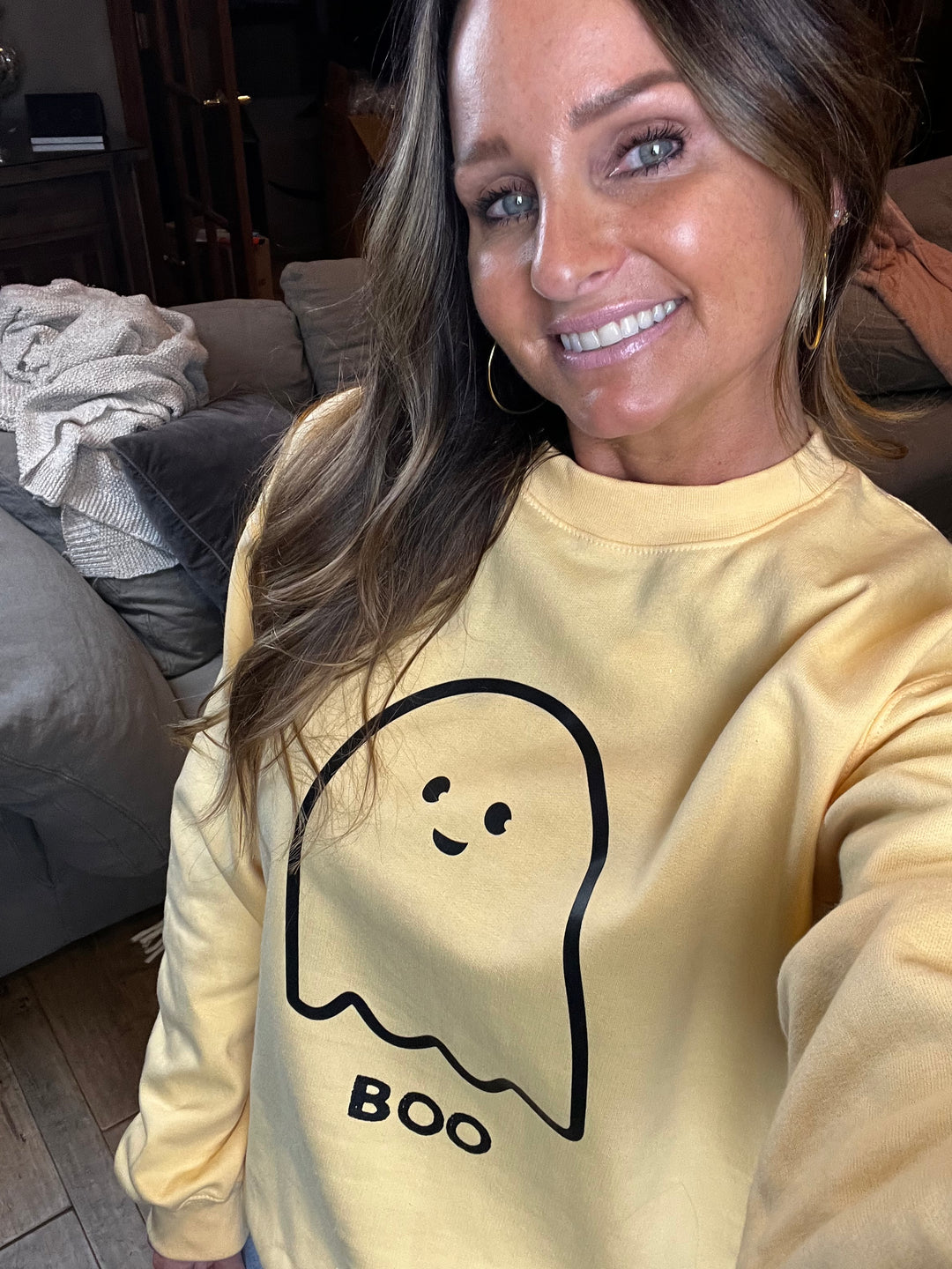 Person wearing a yellow sweatshirt with a ghost design and 'BOO' text.
