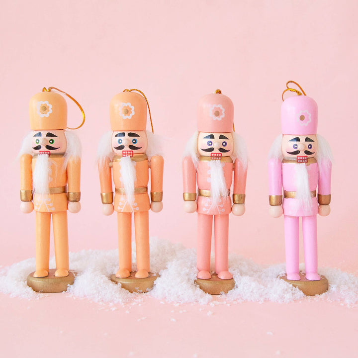 Four wooden nutcracker figurines in pink and peach colors, holiday ornaments, Christmas